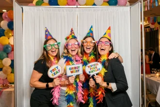 Groupe d'adultes joyeux prenant la pose dans une borne photomaton lors d'un anniversaire festif avec accessoires colorés
